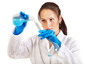 Woman with a brown ponytail in a lab coat pouring blue liquid from a beaker into a test tube.